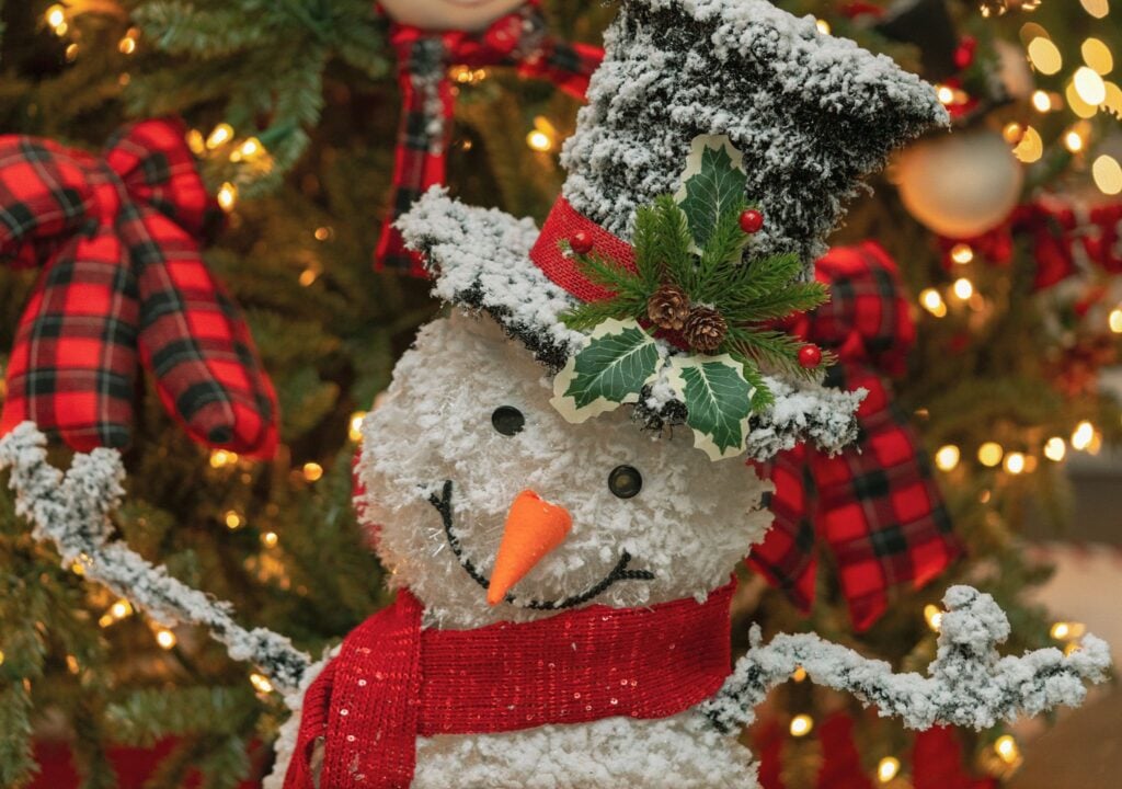 Plaid snowman ornament on a lit Christmas tree at ChristmasLand
